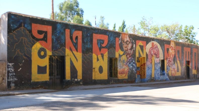 Mural callejero con la palabra Angualasto, cerros y un rostro.